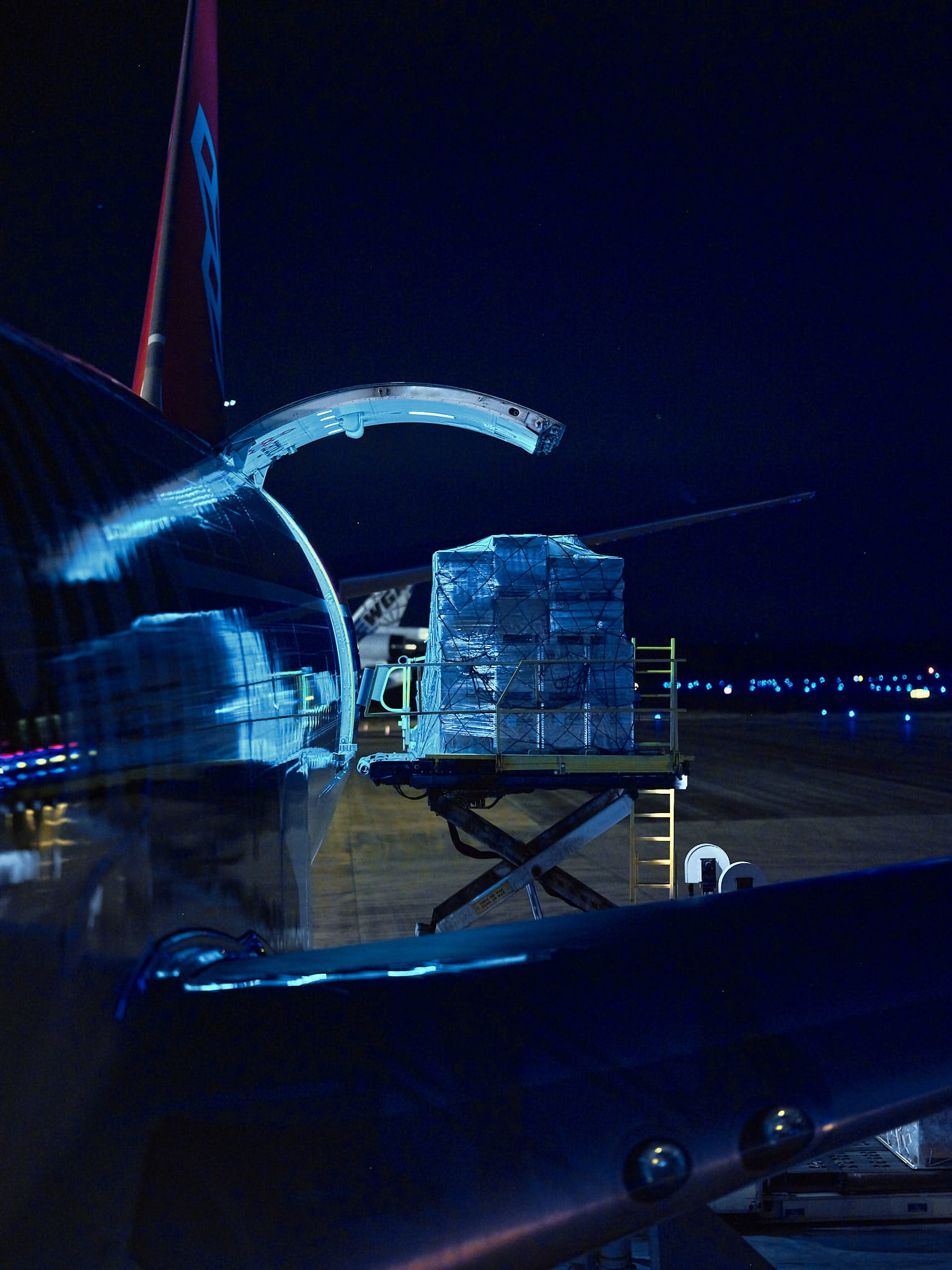 A plane being loaded with cargo in darkness.